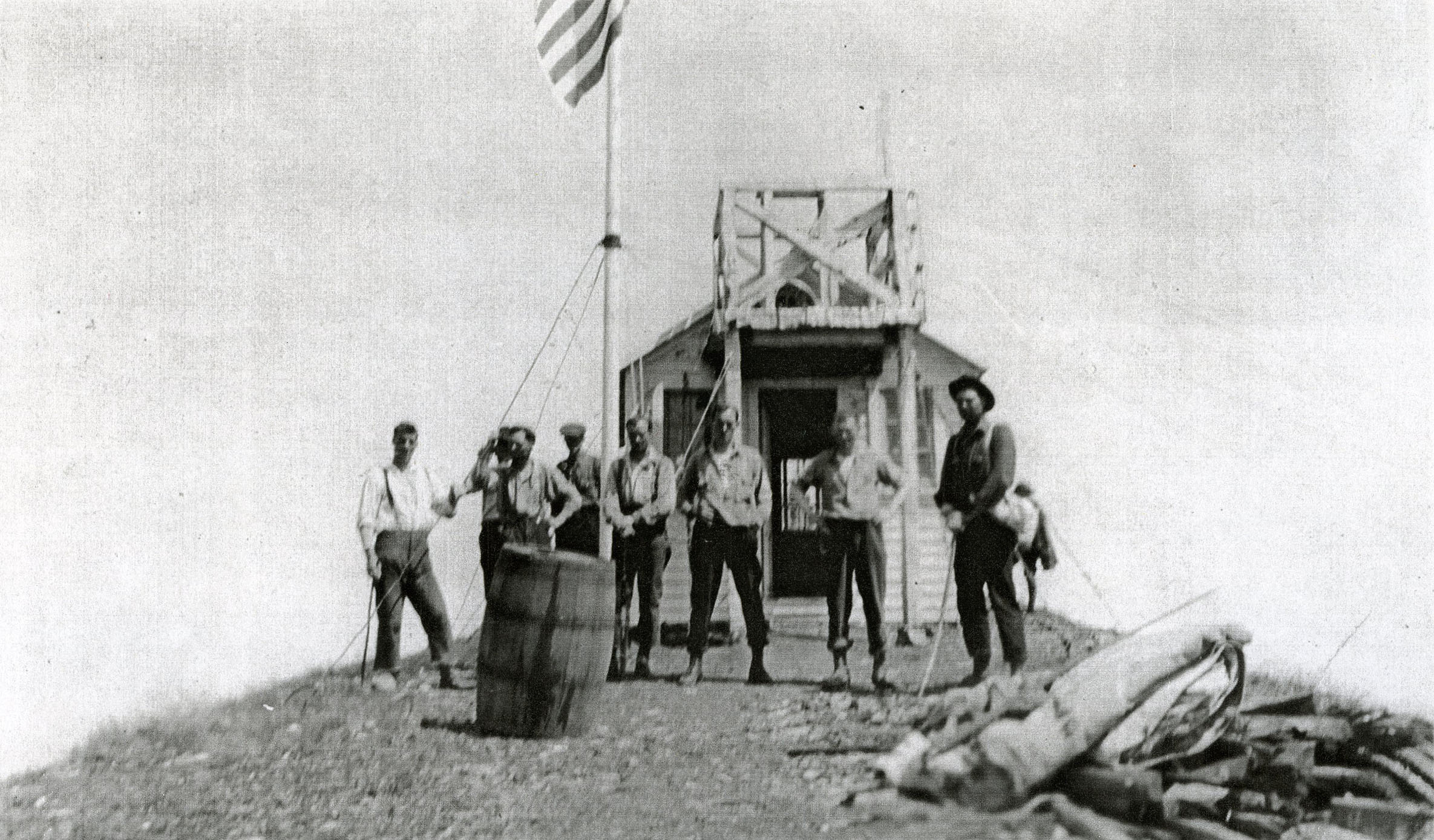 Men raise flag on Saddle Mountain.
